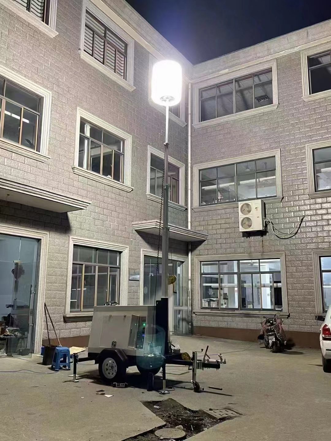 Mobile lighting tower illuminating a building at night
